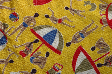 detail of vintage beach bag made of bright yellow 1950s towelling fabric with beach umbrella and male & female swim-suited figures pattern