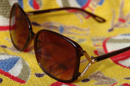 detail of vintage beach bag made of bright yellow 1950s towelling fabric with beach umbrella and male & female swim-suited figures pattern with vintage Biba sunglasses sitting on top