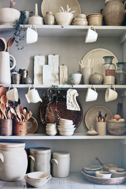 shelves covered in vintage cream coloured pottery, crockery and wooden utensils shelves covered in vintage cream coloured pottery, crockery and wooden utensils