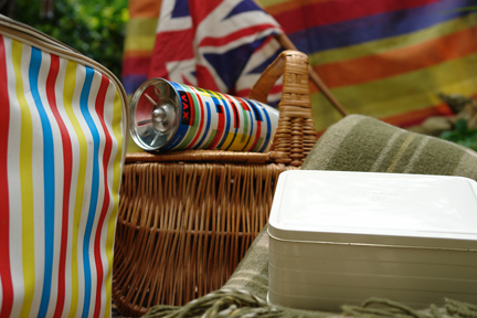 picnic setting with vintage wicker basket, thermos flask, picnic blanket and union jack flag