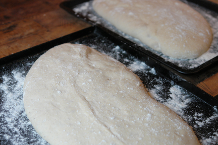 two uncooked, homemade ciabatta loaves prooving before getting put in the oven