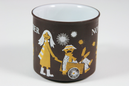 detail from a vintage "November" mug produced by Hornsea Pottery showing a girl pushing a wheelbarrow holding a guy on Fireworks Night detail from a vintage "November" mug produced by Hornsea Pottery showing a girl pushing a wheelbarrow holding a guy on Fireworks Night