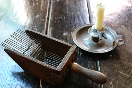Mystery object with antique metal candleholder on pine topped table