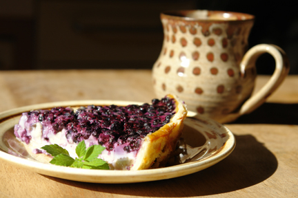 plate with a slice of bilberry tart and cup of tea