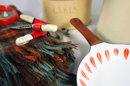 collection of recently acquired H is for Home shop stock including a Suzie Cooper coffee set, Cathrineholm Lotus frying pan, Tala cake tin, orange goose necked desk lamp and checked picnic blanket