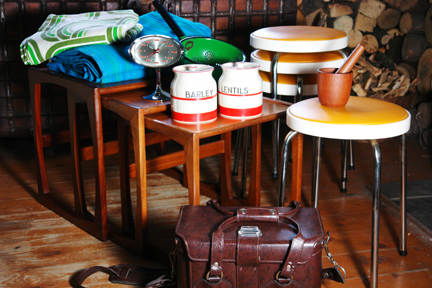 selection of recently acquired vintage items including a G Plan nest of teak tables, orange seated Chair Centre stacking stools, green & blue striped curtains, Rhythm pedestal clock, Scandinavian teak mortar & pestle, Hinomoto vinyl camera bag and red & white Kleen Kitchen Ware jars