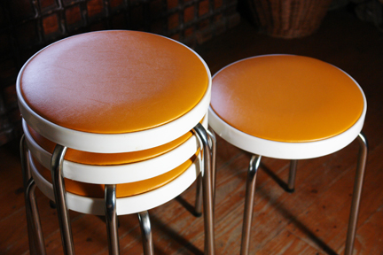 detail of set of 4 orange seated Chair Centre stacking stools