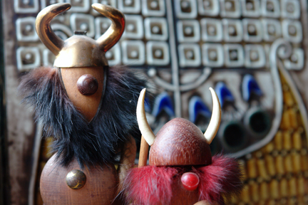 pair of vintage Viking noggin figures in front of a Lisa Larson ceramic tile of a Viking ship